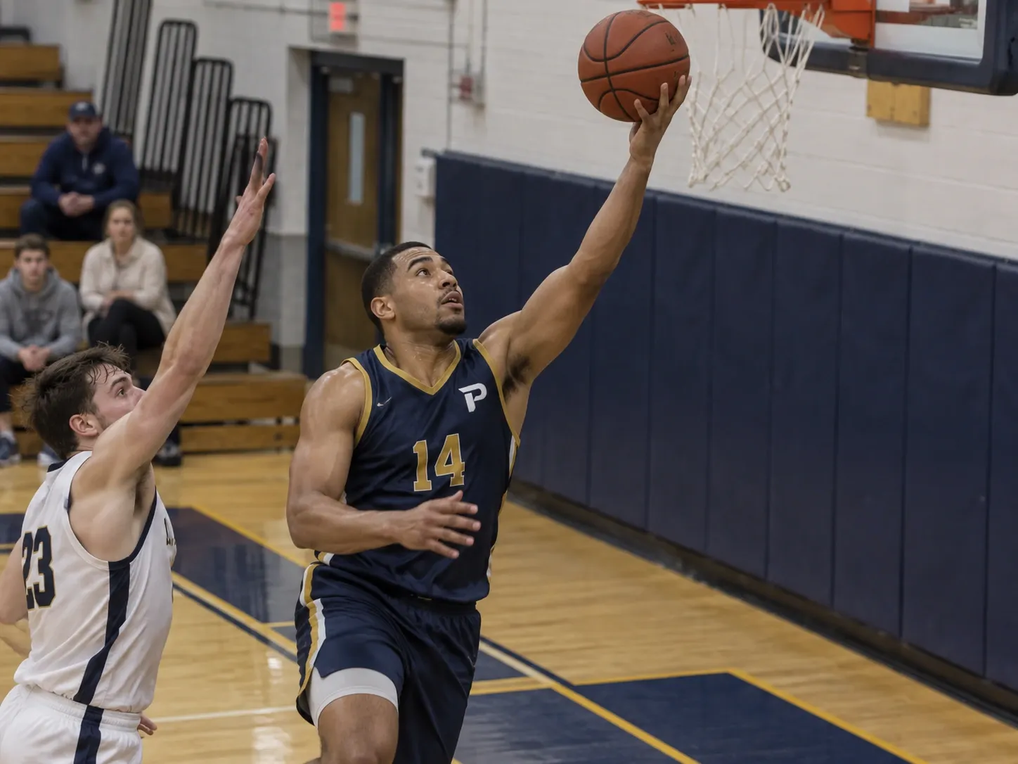 A basketball player in a navy Ironclads jersey driving to the basket.