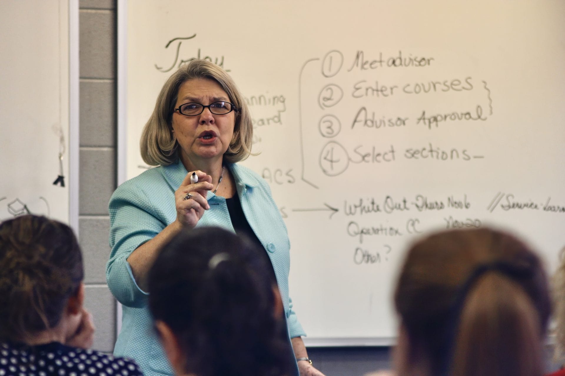 An instructor at a whiteboard talking through steps with a class.