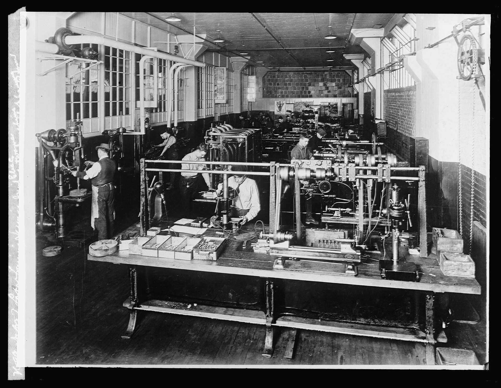 A historic photo of students at benches in a machine-shop training room.