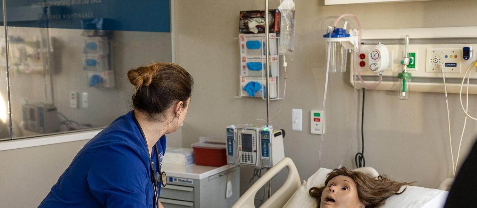 Dietetics — A nursing student checking on a patient simulator in a hospital-style training room.