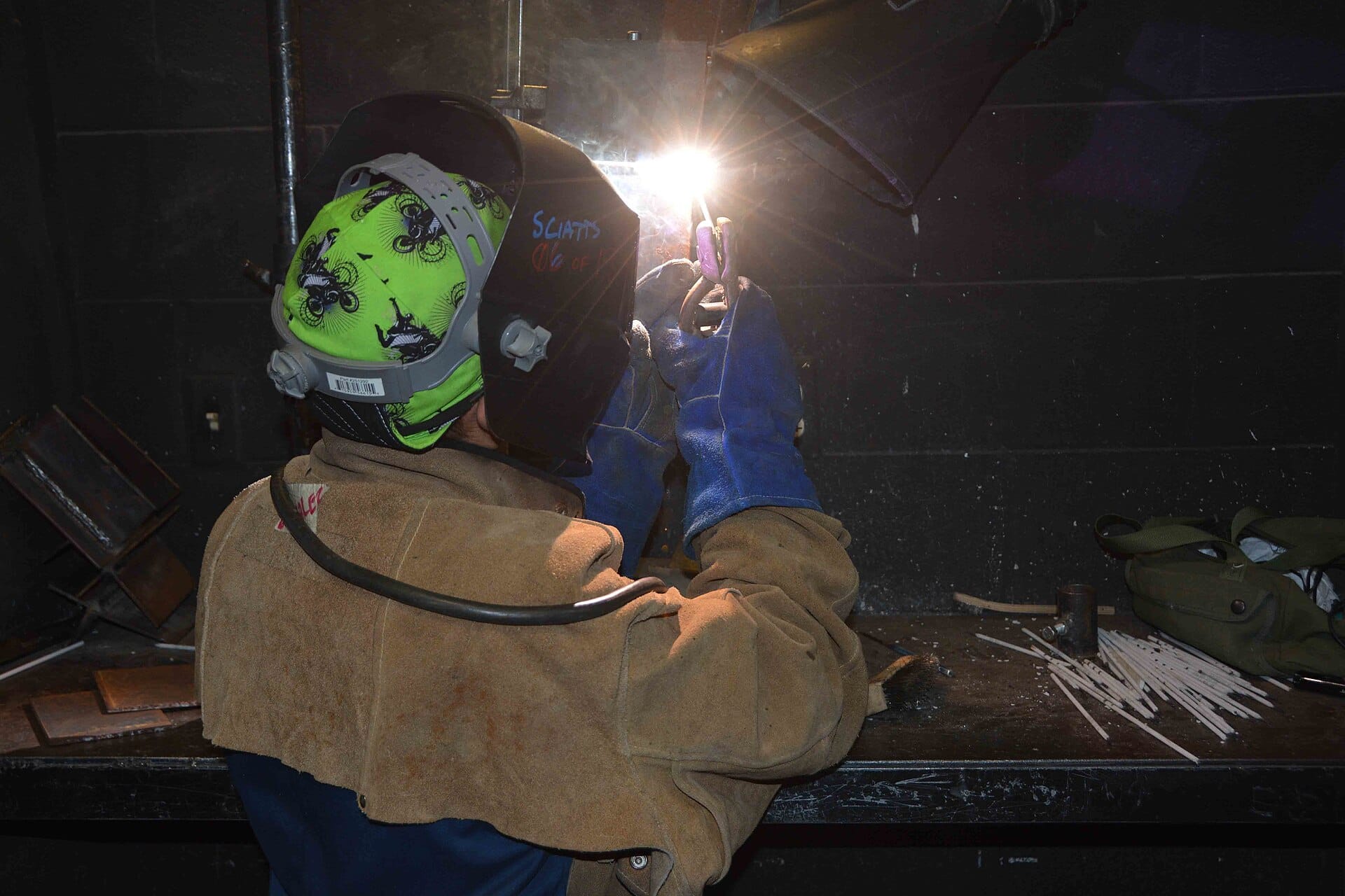 A student welding under a fume hood.